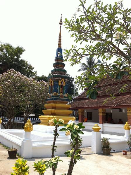 Gilded and enameled stupa in a temple courtyard, among flowering trees
