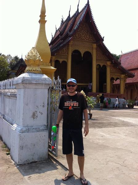 Tourist by white wall and golden stupa in front of the temple