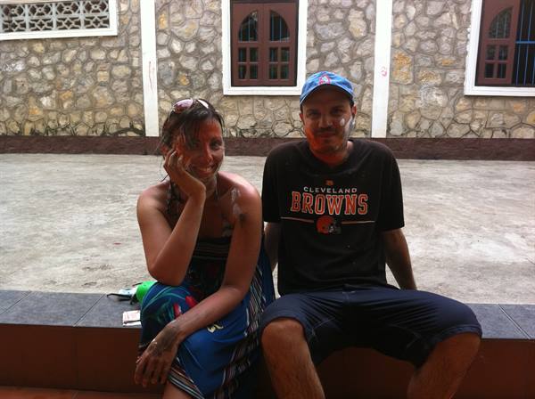 Couple with thanaka-painted faces sitting on a stone ledge by a rock wall