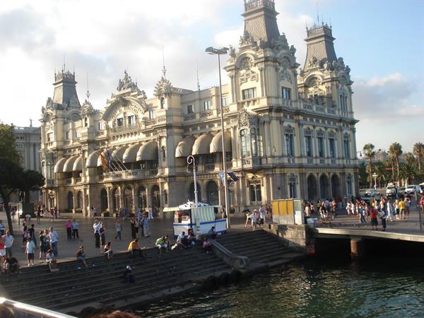 Tourists on steps in front of the historic Port Vell building, Barcelona