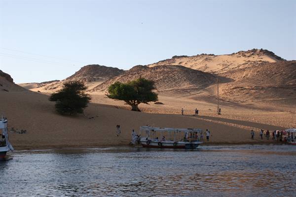 Tourists disembark from a boat on the sandy Nile riverbank at Aswan