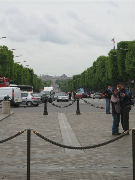 Tourist couple takes a selfie on a tree-lined Paris avenue busy with cars