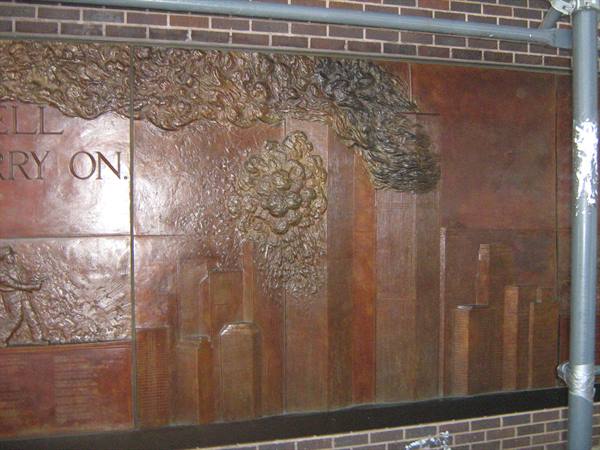 Bronze relief of the Twin Towers with sculpted smoke, mounted on a brick wall