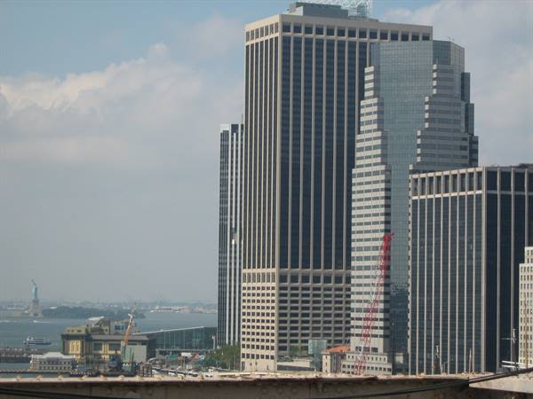 Glass skyscrapers of Lower Manhattan, the Statue of Liberty far across the bay