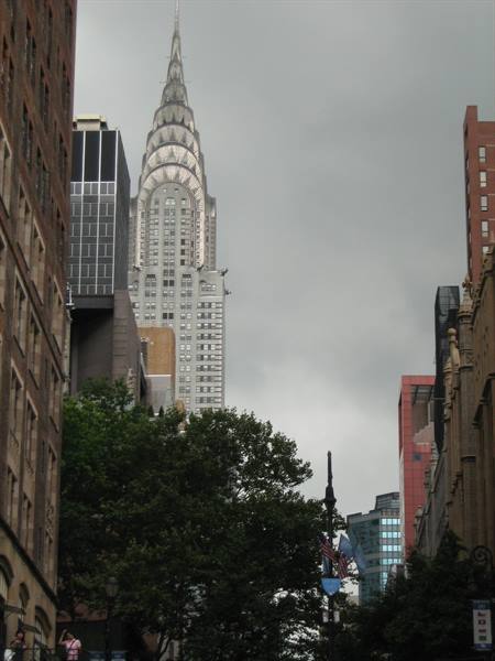 The Chrysler Building rises among New York skyscrapers under a grey sky