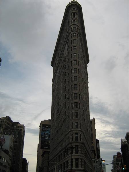 New York's Flatiron Building rises narrow against a cloudy sky