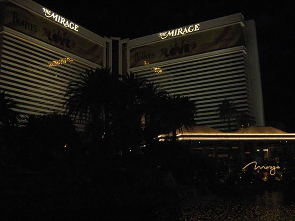 The Mirage hotel lit at night with golden signs and dark palm trees