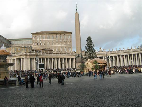 St. Peter's Square with Egyptian obelisk, nativity scene and tourists under cloudy sky
