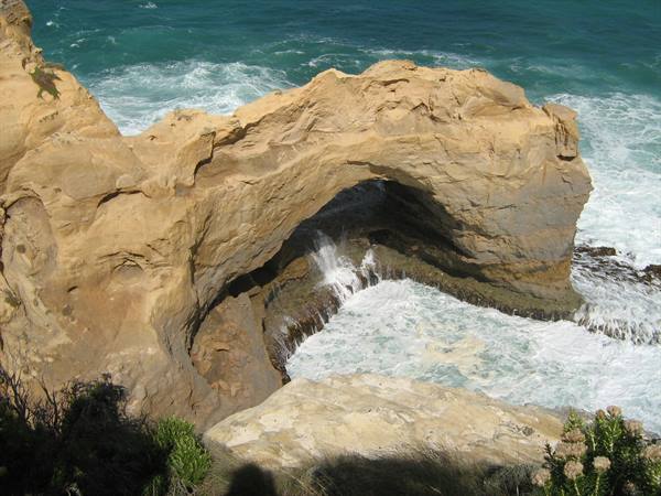 Limestone rock arch over the ocean, white waves crashing beneath it