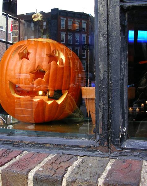 Carved Halloween pumpkin with star cutouts behind a shop window