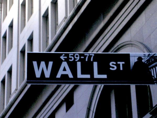 Wall St street sign in front of a stone skyscraper, daylight