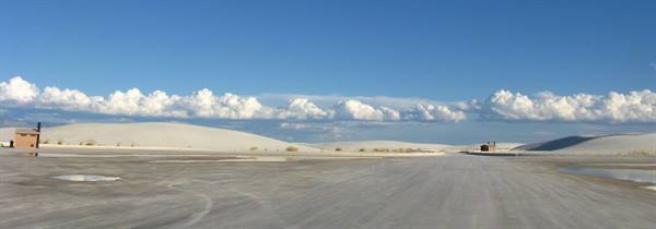 White Sands: strada piatta tra dune di gesso bianco, nuvole gonfie e casette adm
