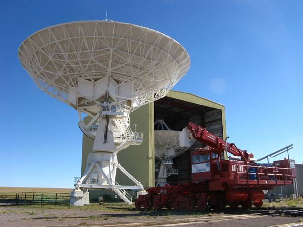 Very Large Array: antenna radio in acciaio bianco accanto al trasportatore rosso