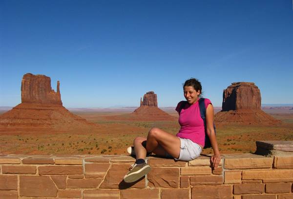 Ragazza seduta su muretto di pietra davanti alle mesas di Monument Valley