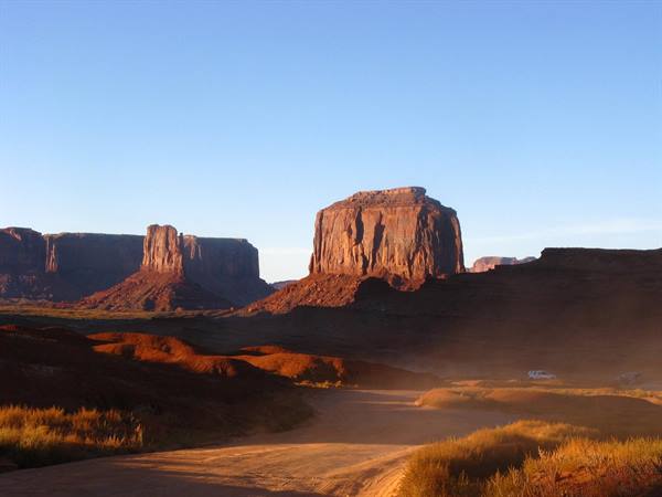 Monument Valley: sentiero polveroso verso i mesa rossi al mattino