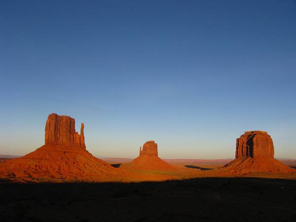 Monument Valley: i masti rossi si illuminano sotto il cielo blu