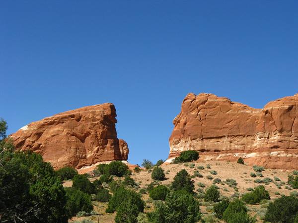 Pareti di arenaria rossa tra ginepri, luce intensa a Monument Valley