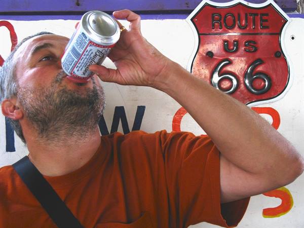 Uomo che beve una Budweiser accanto al cartello Route 66