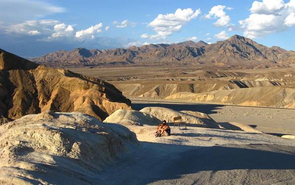 Turista seduto sulle colline di rocce gialle di Zabriskie Point, Death Valley