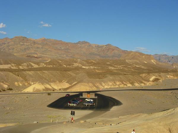 Parcheggio con auto tra colline aride color ocra, Death Valley