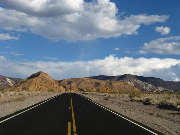 Strada asfaltata tra colline aride e banchi di nuvole, Death Valley