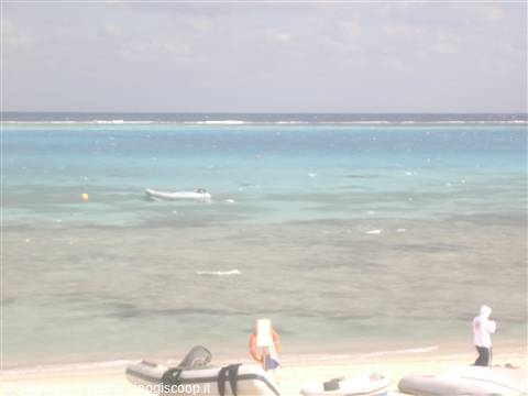 Turquoise sea with inflatable boats on the beach and a small anchored boat