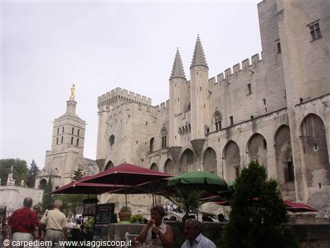 Tourists under umbrellas in front of the Papal Palace in Avignon, pale stone