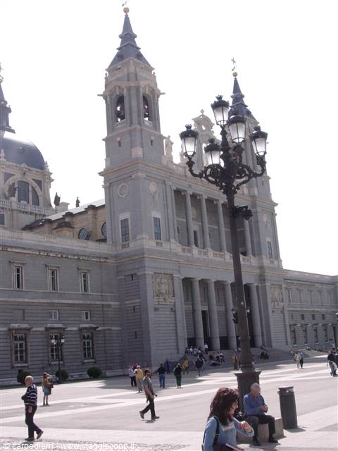 Almudena Cathedral in Madrid, people walk across the square under a lamppost