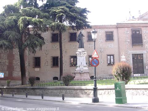 Statue on marble pedestal in front of historic building, trees and lamppost