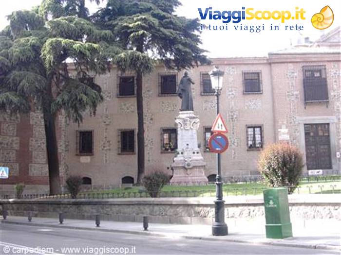 Statue on marble pedestal in front of historic building, trees and lamppost