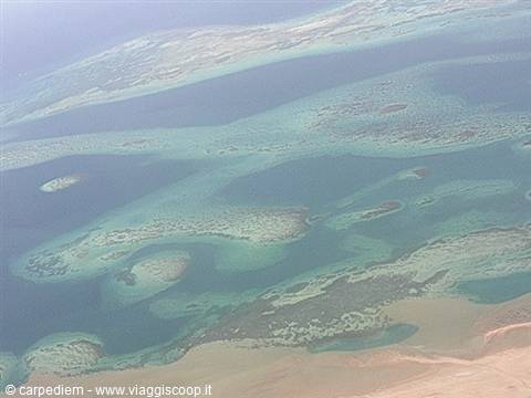 Coral reef seen from the plane, turquoise water between rocks and sand