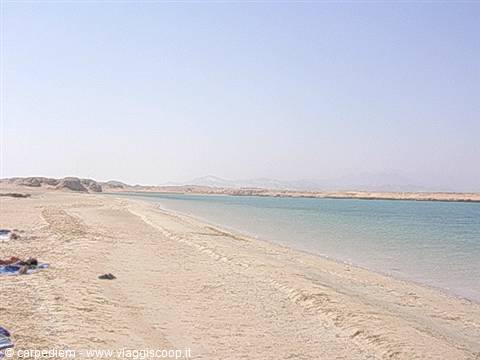 White sandy beach with turquoise water and hazy mountains