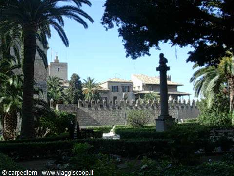 Garden with palms, statue column and old stone walls in Palma de Mallorca