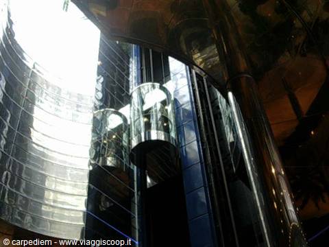 Glass panoramic elevators inside a cruise ship, lit by daylight