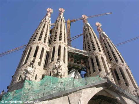 Sagrada Família towers in Barcelona with cranes and scaffolding against a blue sky