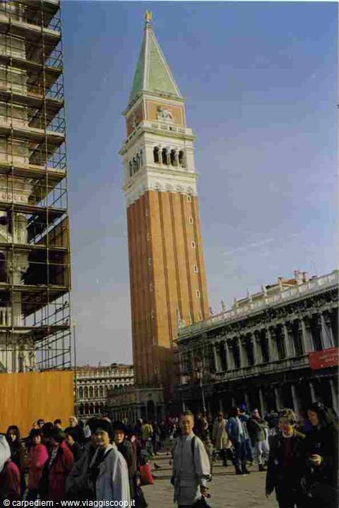 Tourists crowd St Mark's Square in Venice beneath the bell tower, scaffolding on the left