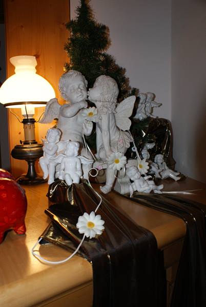 White angel figurines and lit oil lamp on wooden cabinet