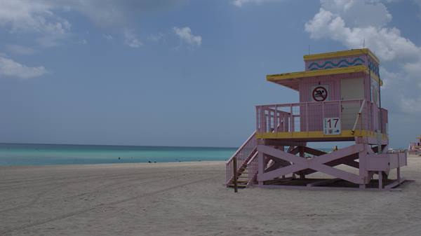Pink and yellow lifeguard tower number 17 on the sand by the ocean