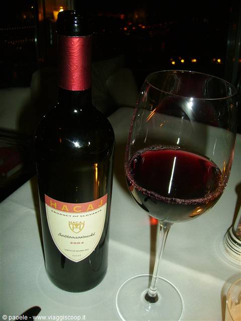 Bottle of Hacaj 2004 red wine and full glass, night in restaurant