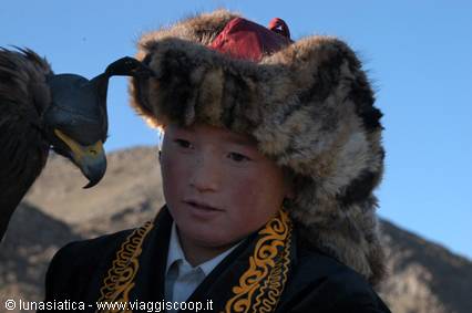 Young eagle hunter in fur hat next to a golden eagle