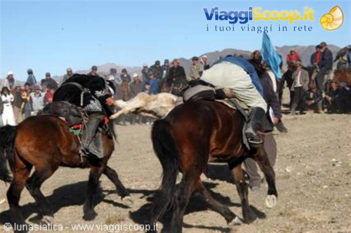 Horsemen struggling for the goat carcass in a buzkashi match, crowd on arid hills