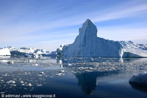 Large iceberg floating on icy sea beneath blue sky