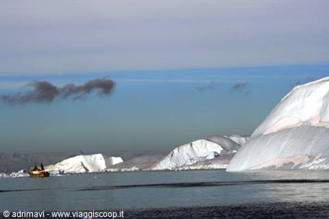 Boat navigating among giant icebergs in Greenland's icy waters