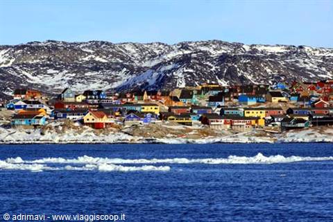 Colorful houses on snowy rocky coast, Arctic sea with drifting ice, Greenland