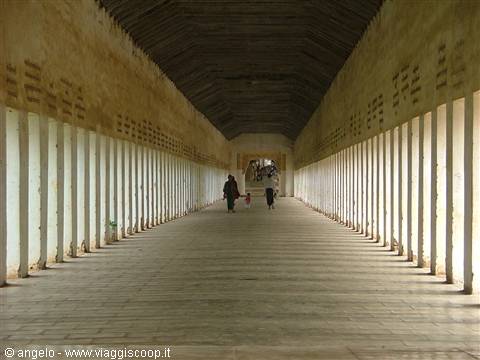 Long corridor with rows of white columns, ochre walls, few walkers