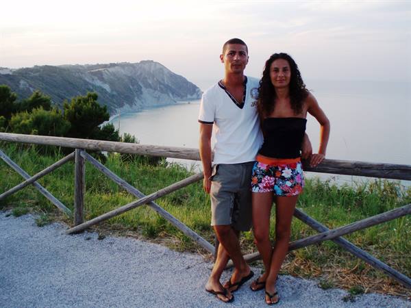 Couple leaning on wooden fence along the Gargano coast at dusk