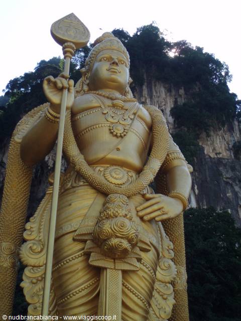 Golden Murugan statue holding a spear in front of Batu Caves