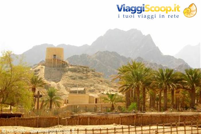 Old mud-brick fort among date palms and rugged arid mountains