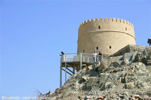 Tourists on the walkway toward the round stone tower of Muttrah Fort