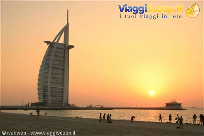 Tourists on the beach at sunset in front of Dubai's Burj Al Arab